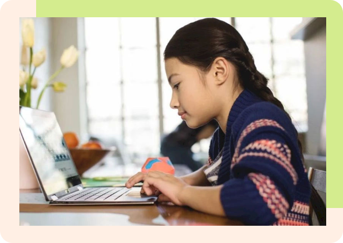 a child sitting at a table working on a laptop